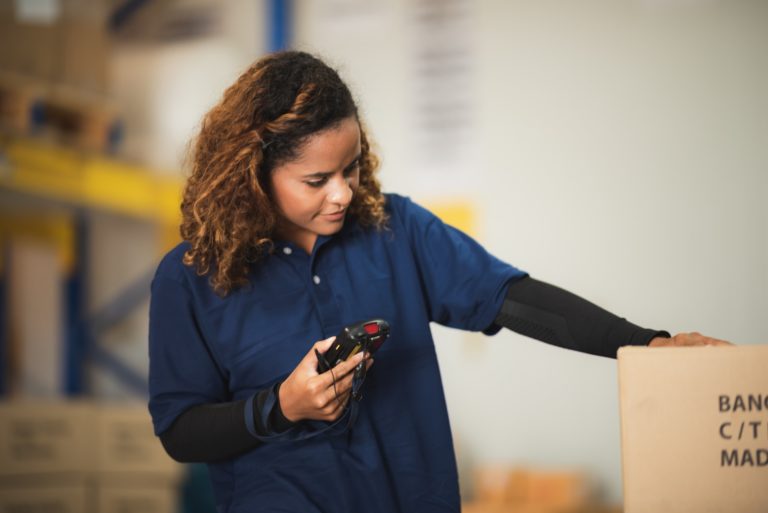 warehouse worker using bar code scanner to analyze newly arrived goods for further placement